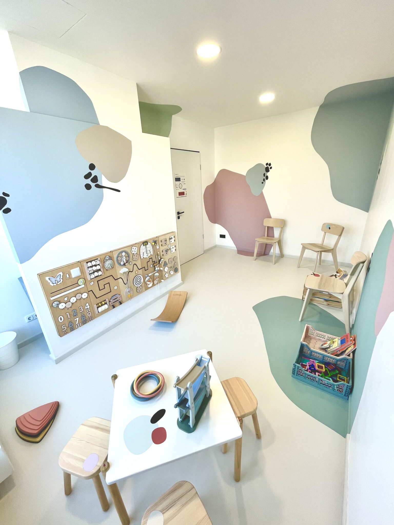 Kinderbereich im Wartezimmer mit Spielwand, Tisch und kleinen Stühlen
