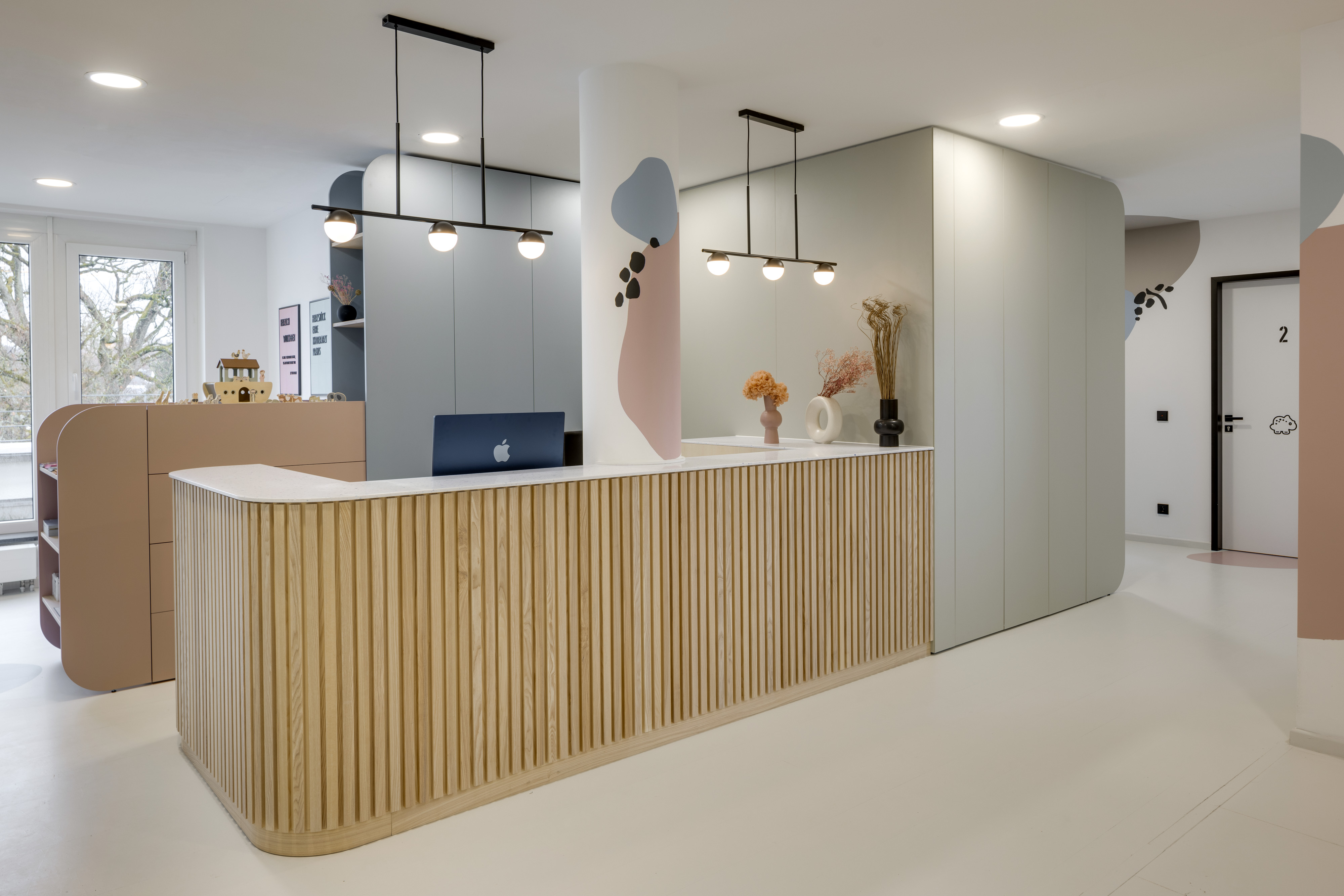 Empfangstresen aus Holz mit Pendelleuchten und farbigen Wanddetails
