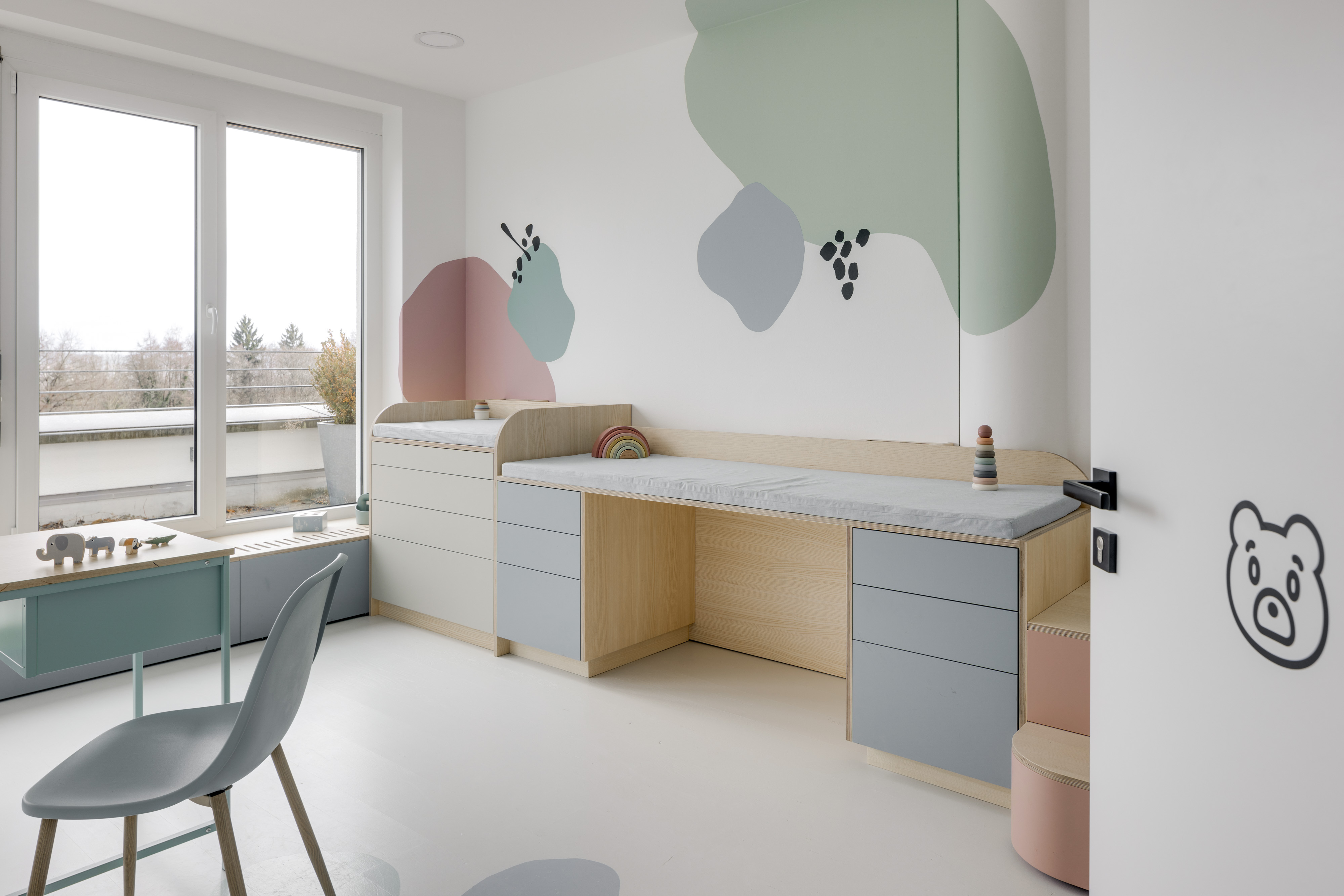 Helles Untersuchungszimmer mit Liege, Wickelplatz und großen Fenstern
